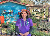 person wearing a purple t-shirt and rainbow coloured hat in plant nursery