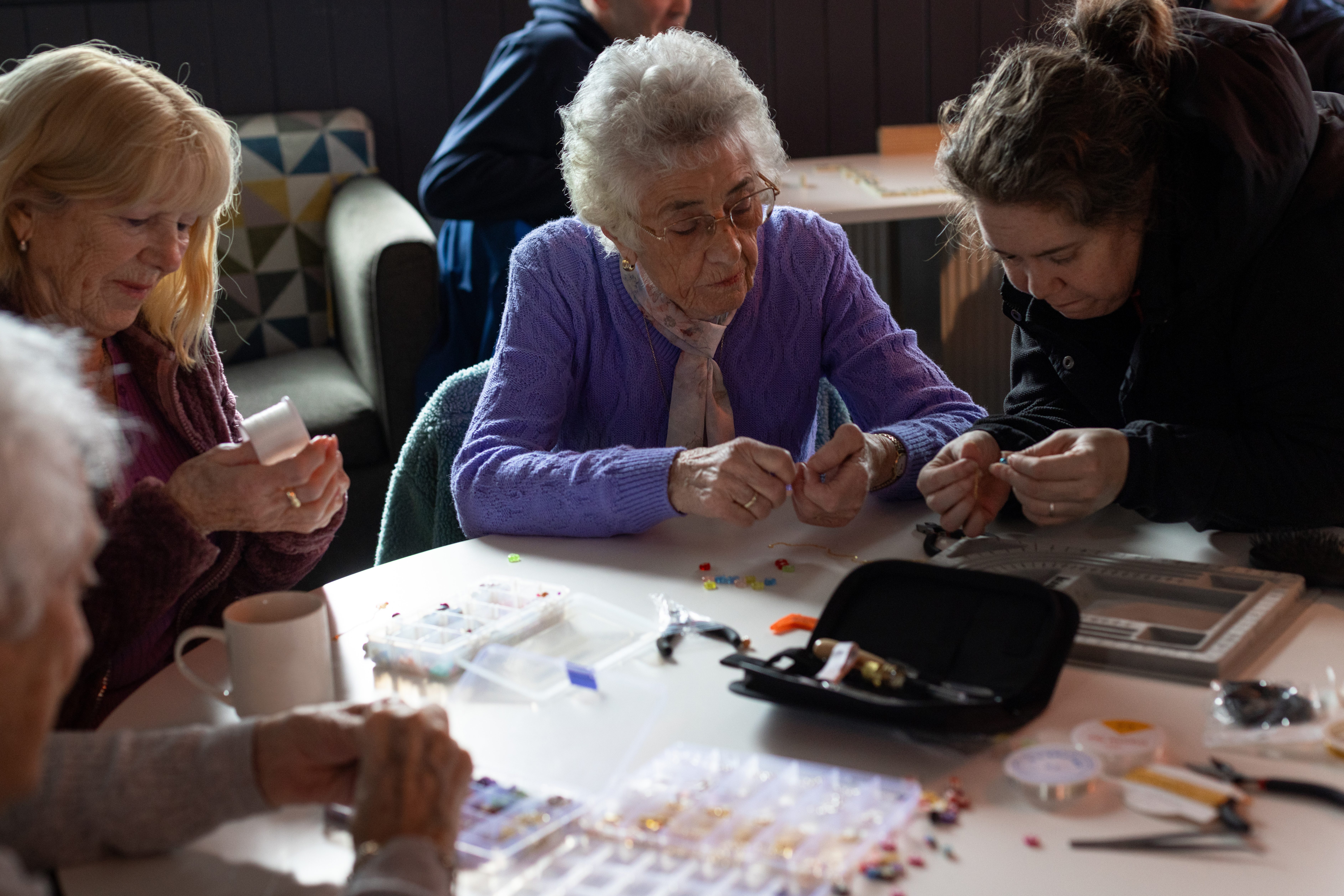 Participants create handmade jewellery together during a community jewellery-making workshop.