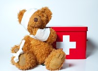 Teddy bear with bandages and a first aid kit