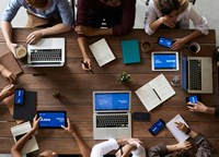 a desk with people and laptops