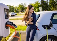 woman leaning on charging electric car