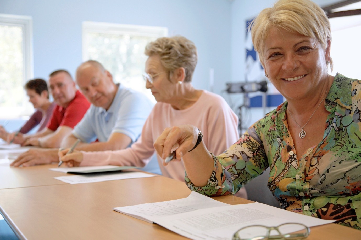 woman smiling with a pen n a group of people making notes