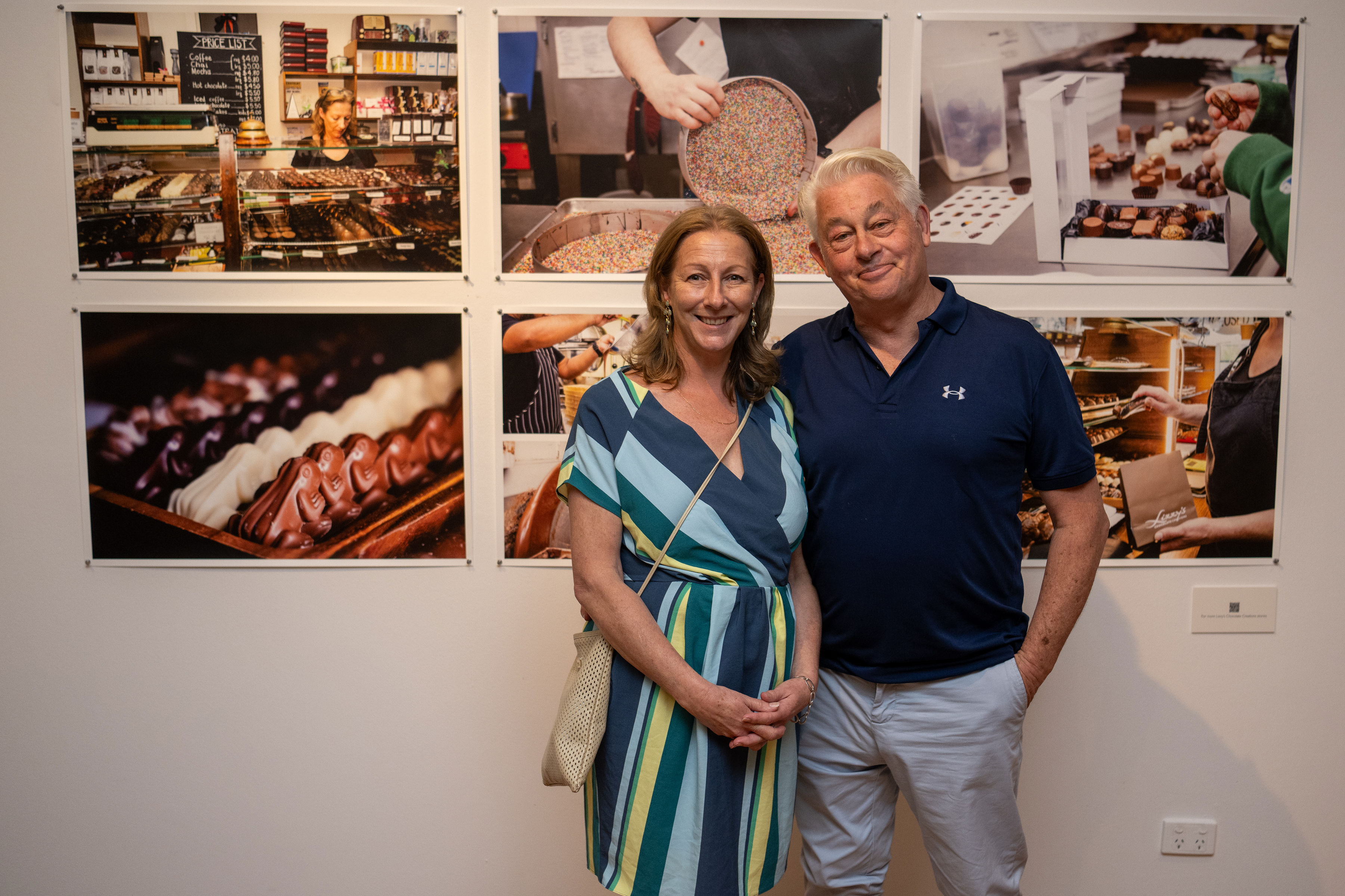 Woman beside man smiling in front of photos