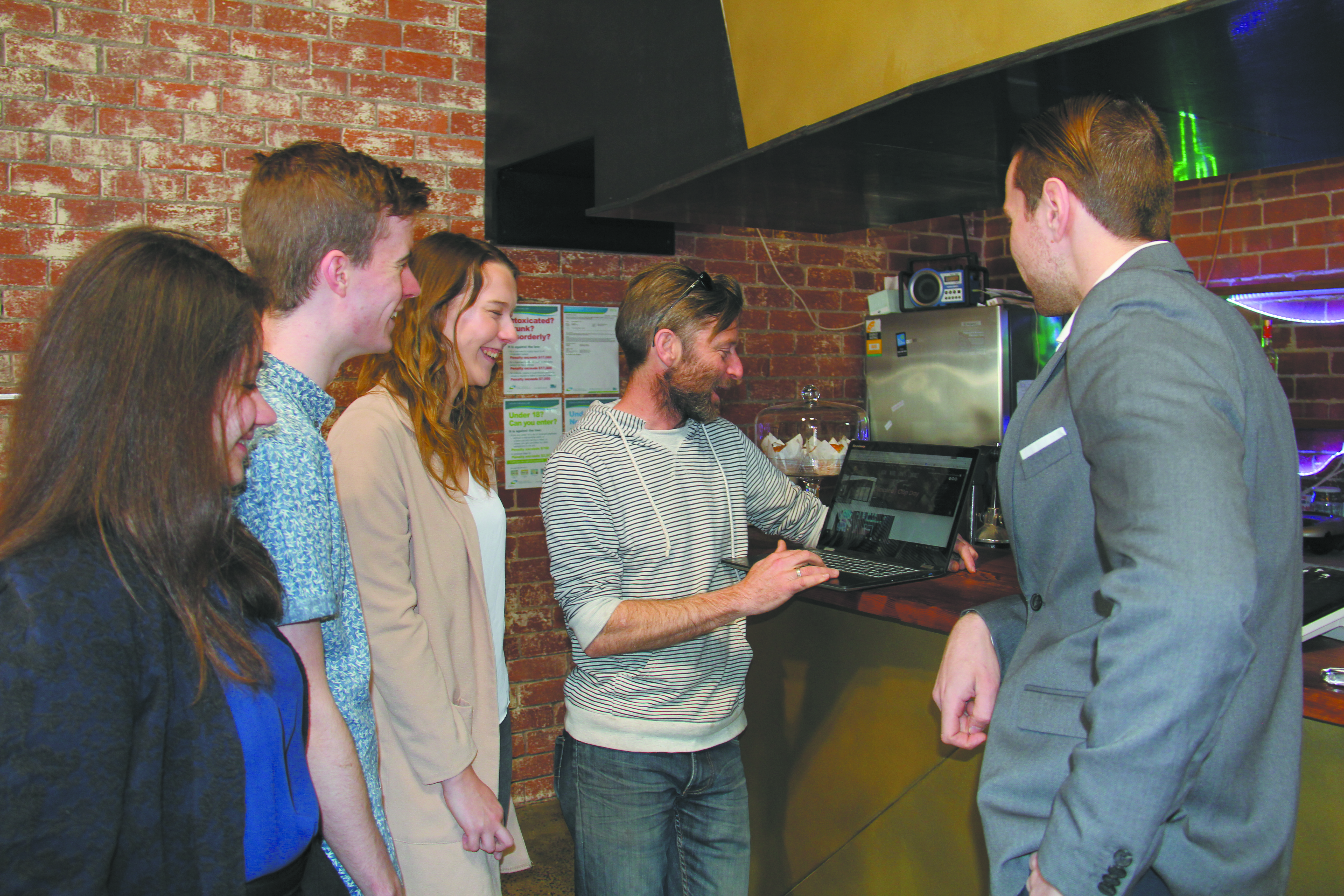 People in discussion with laptop around kitchen
