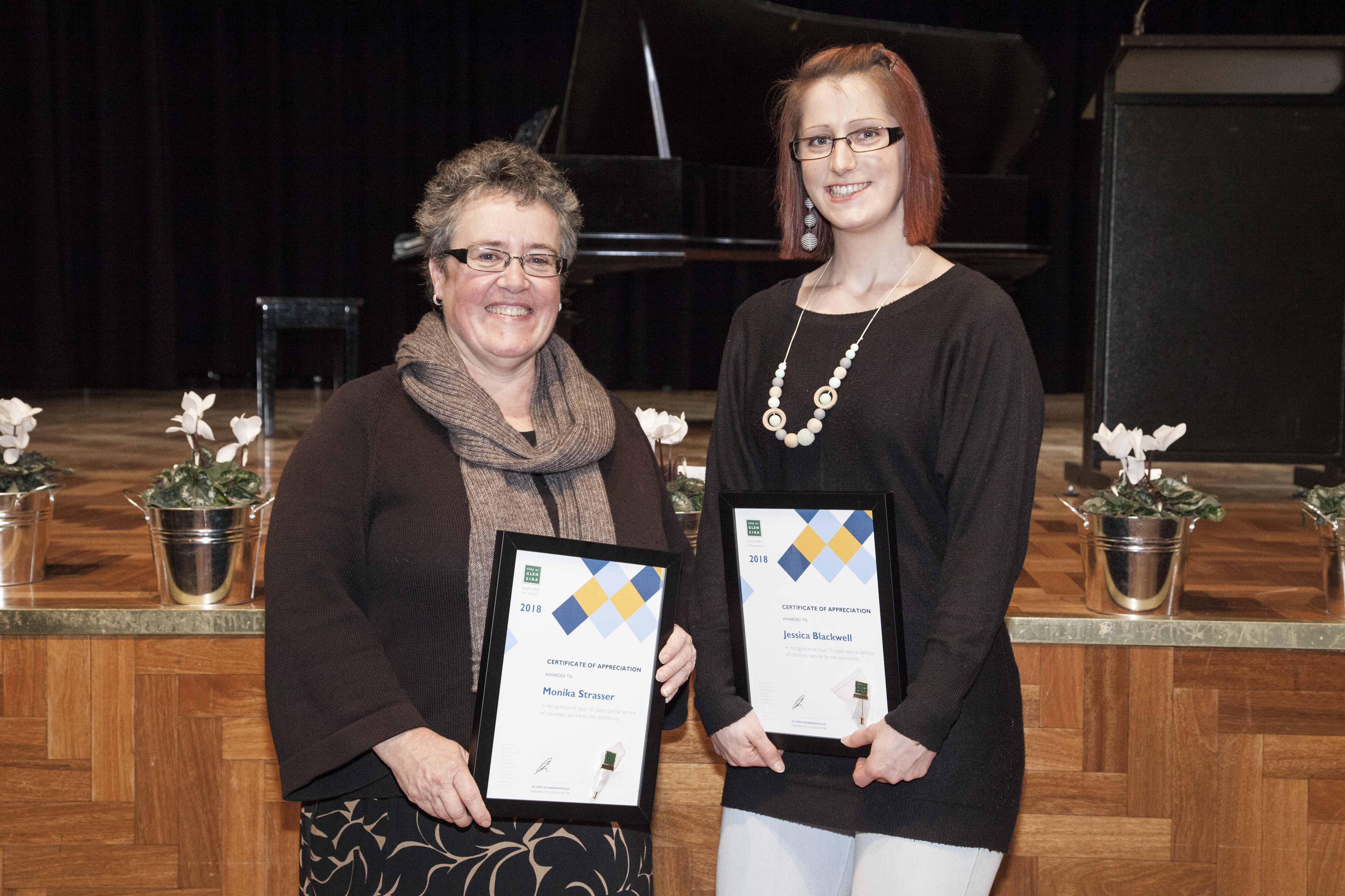 Two volunteers holding awards
