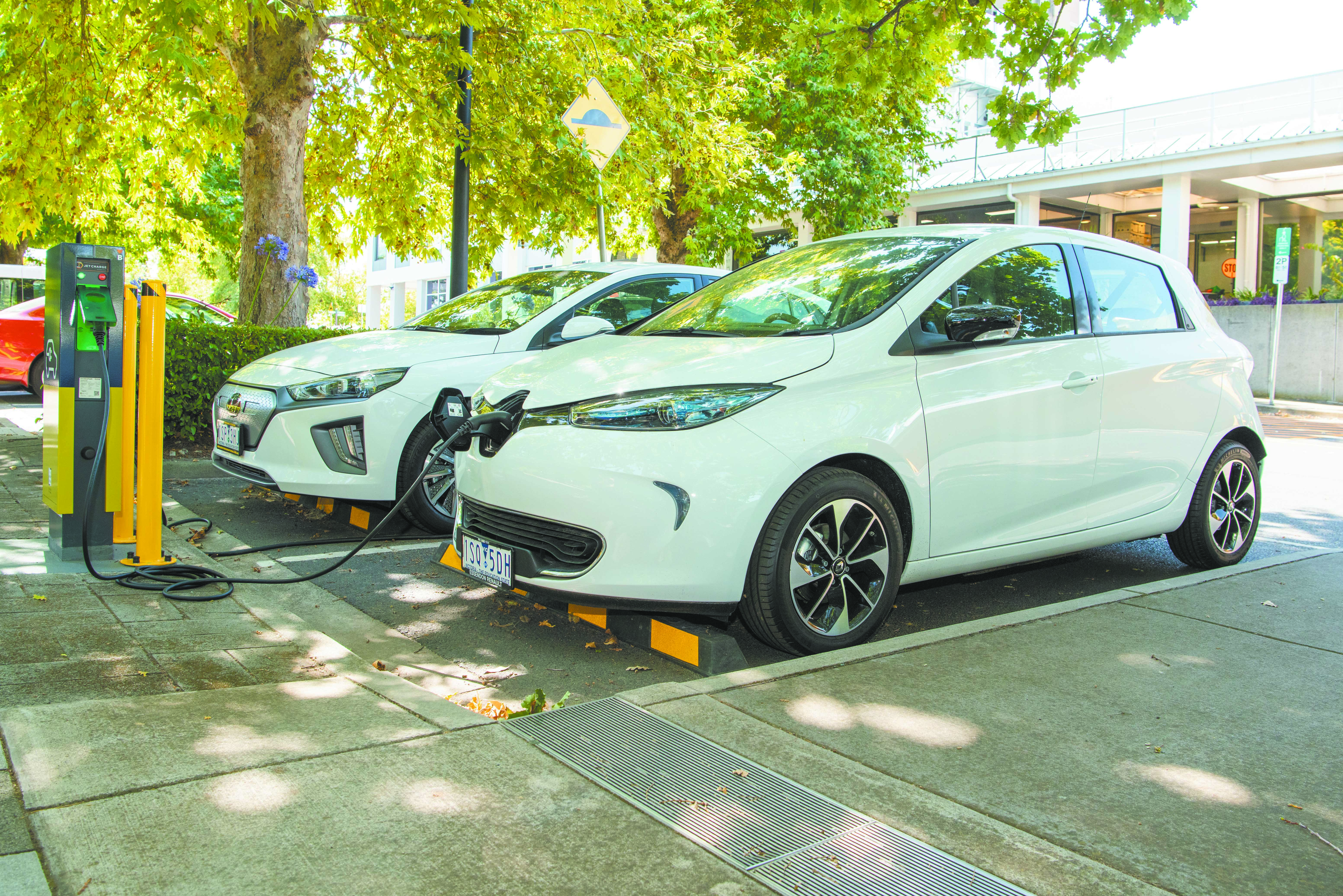 A white Renault Zoe electric car being charged and white Hyundai Ioniq parked next to it