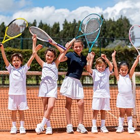 kids on a tennis court holding racquets