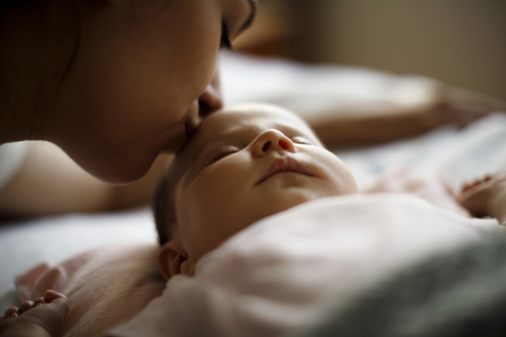 Woman kissing sleeping baby