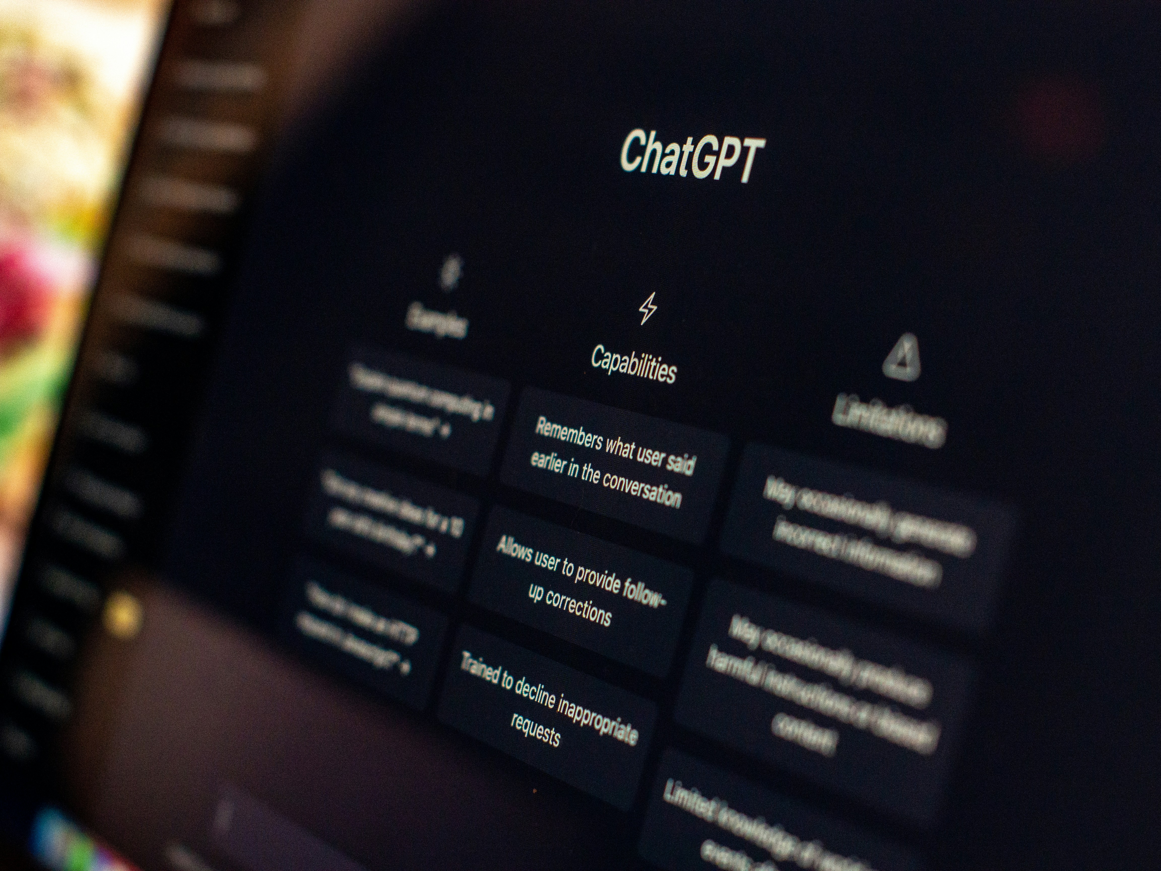 Close-up of a computer screen displaying the ChatGPT interface, showing capability descriptions and menu options in a dark-themed layout.