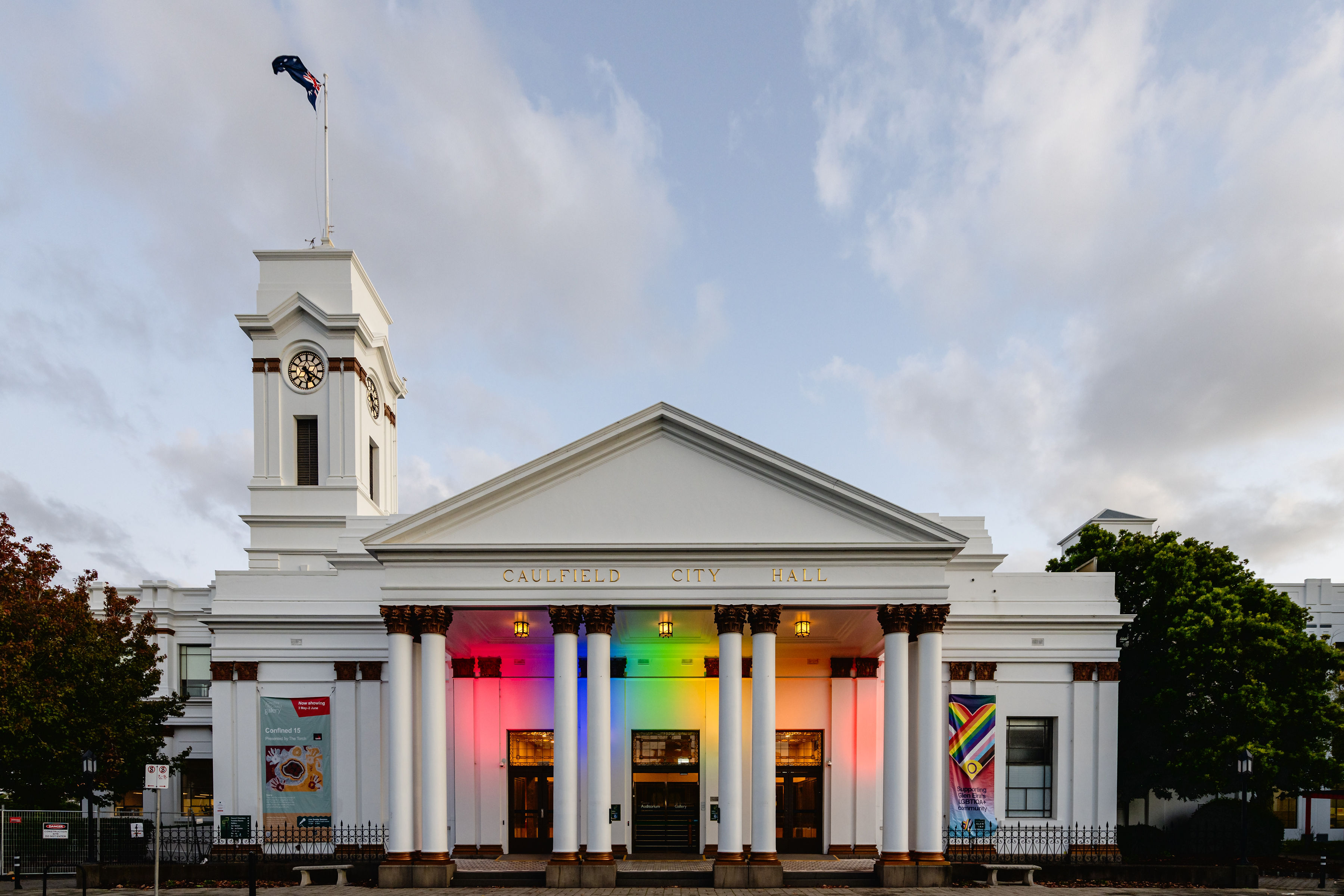 Caulfield City Hall illuminated in rainbow colours, promoting an LGBTIQA+ community event or pride-themed activity.