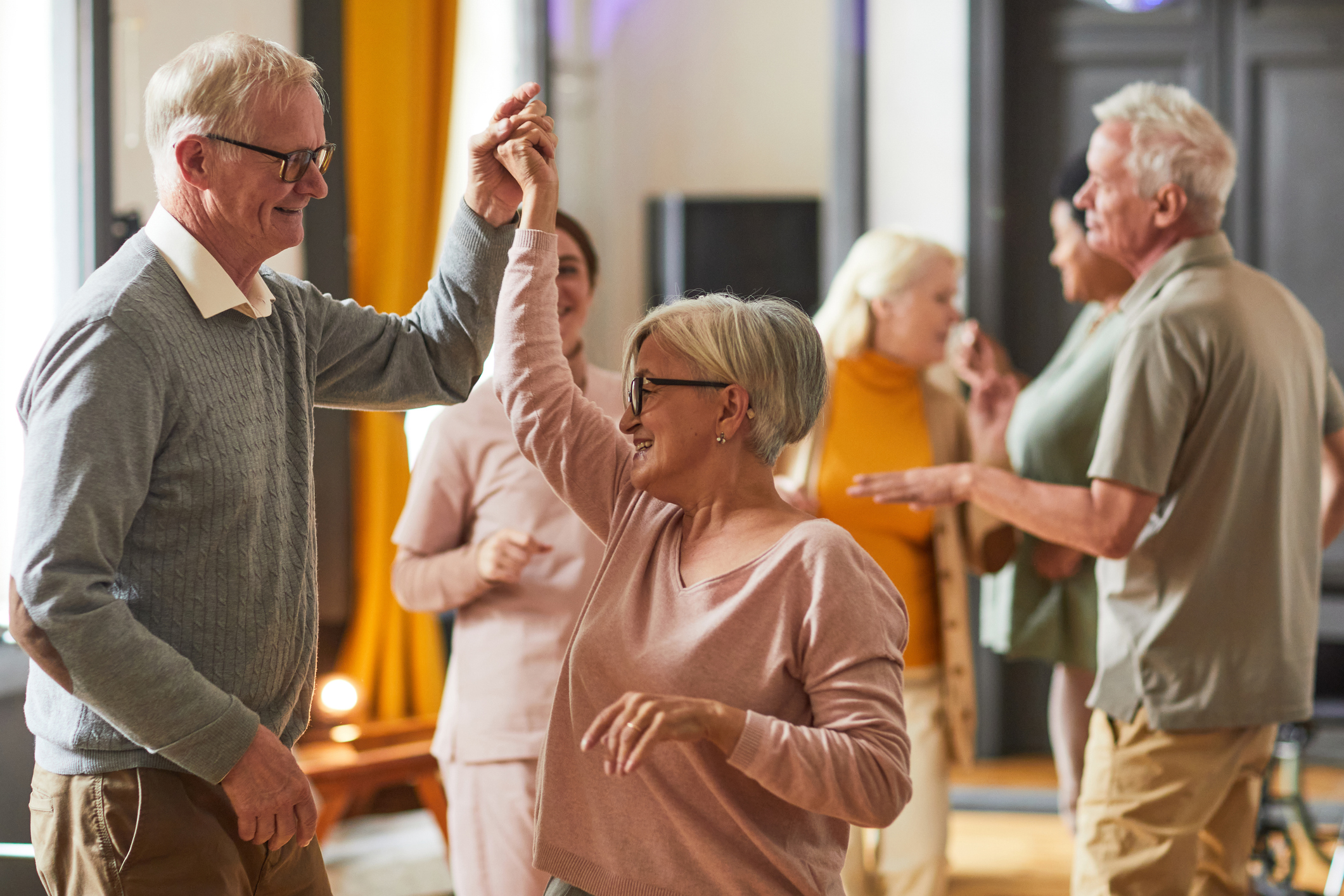 Older adults take part in a social dance session at a community venue.