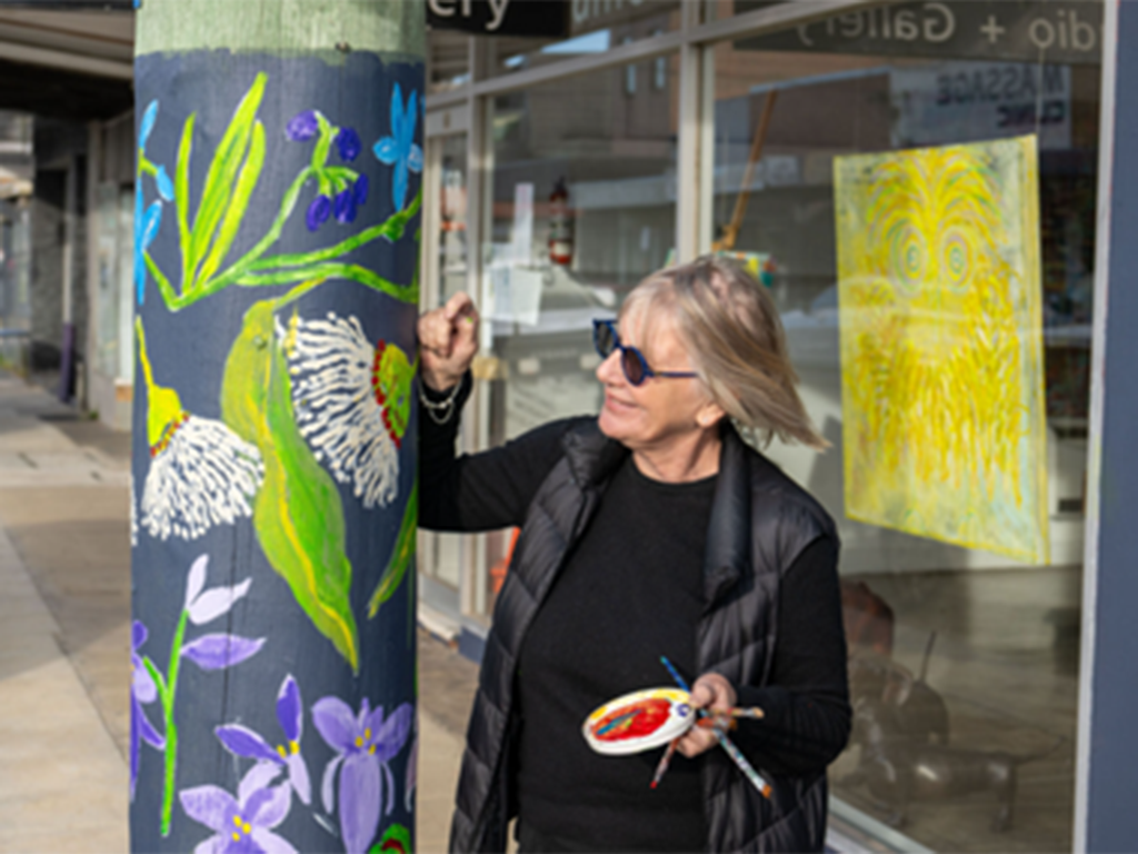 Pamela Irving pictured painting one of the poles outside her art studio