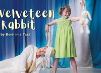 young girl in a green dress holding the bunny ear of an adult dressed as a white rabbit