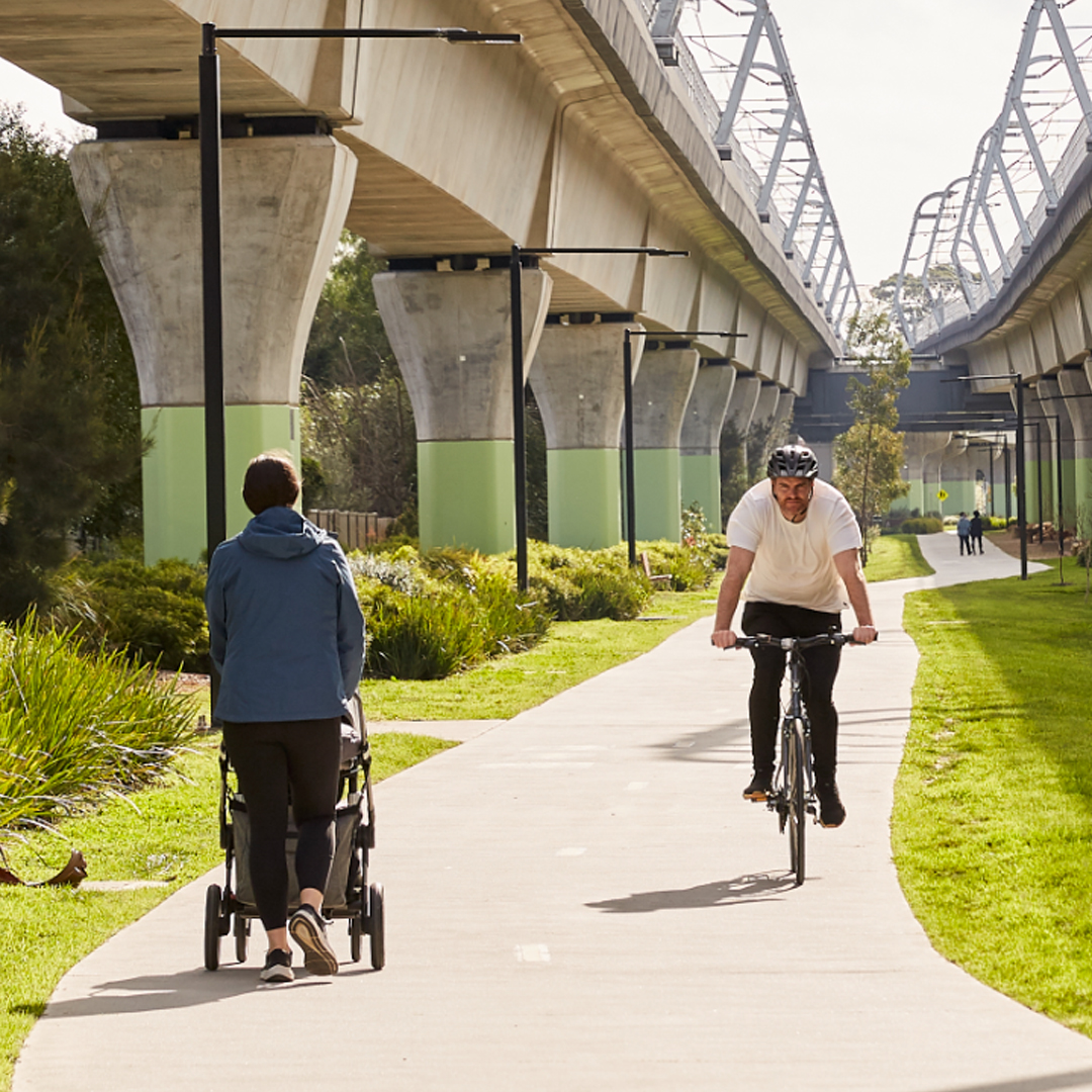 Person pushing a pram and man riding a bike on a shared path