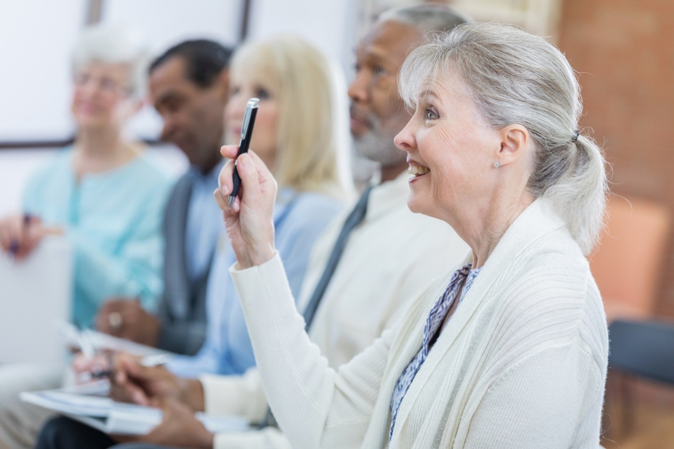 woman in a group raising her hand to ask a question