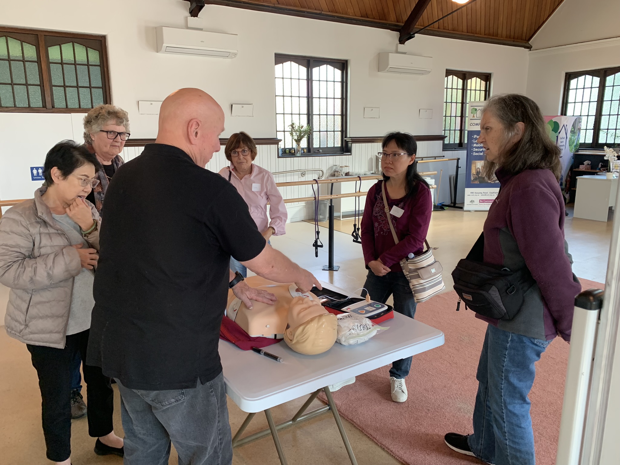 Participants learn CPR and defibrillator use during a hands-on first aid training session with a practice mannequin.