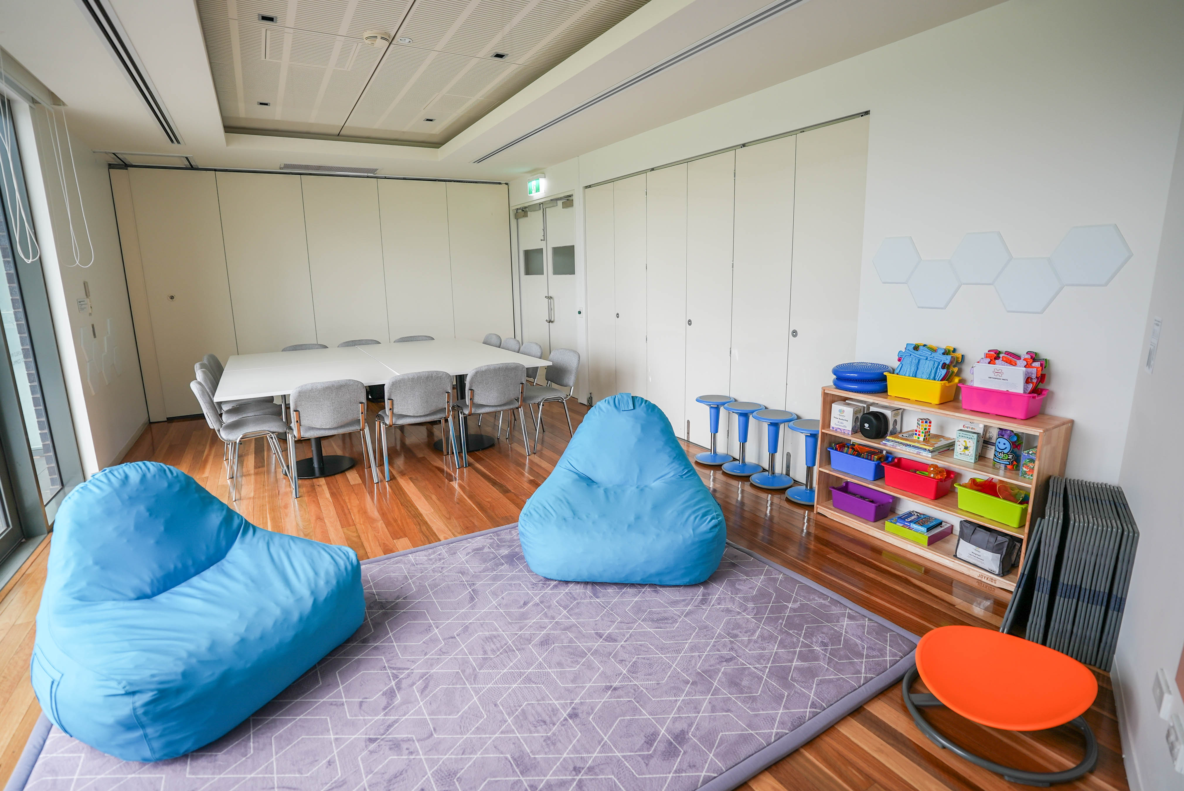 A sensory room with soft seating, beanbags, activity toys and a table and chairs for group use.