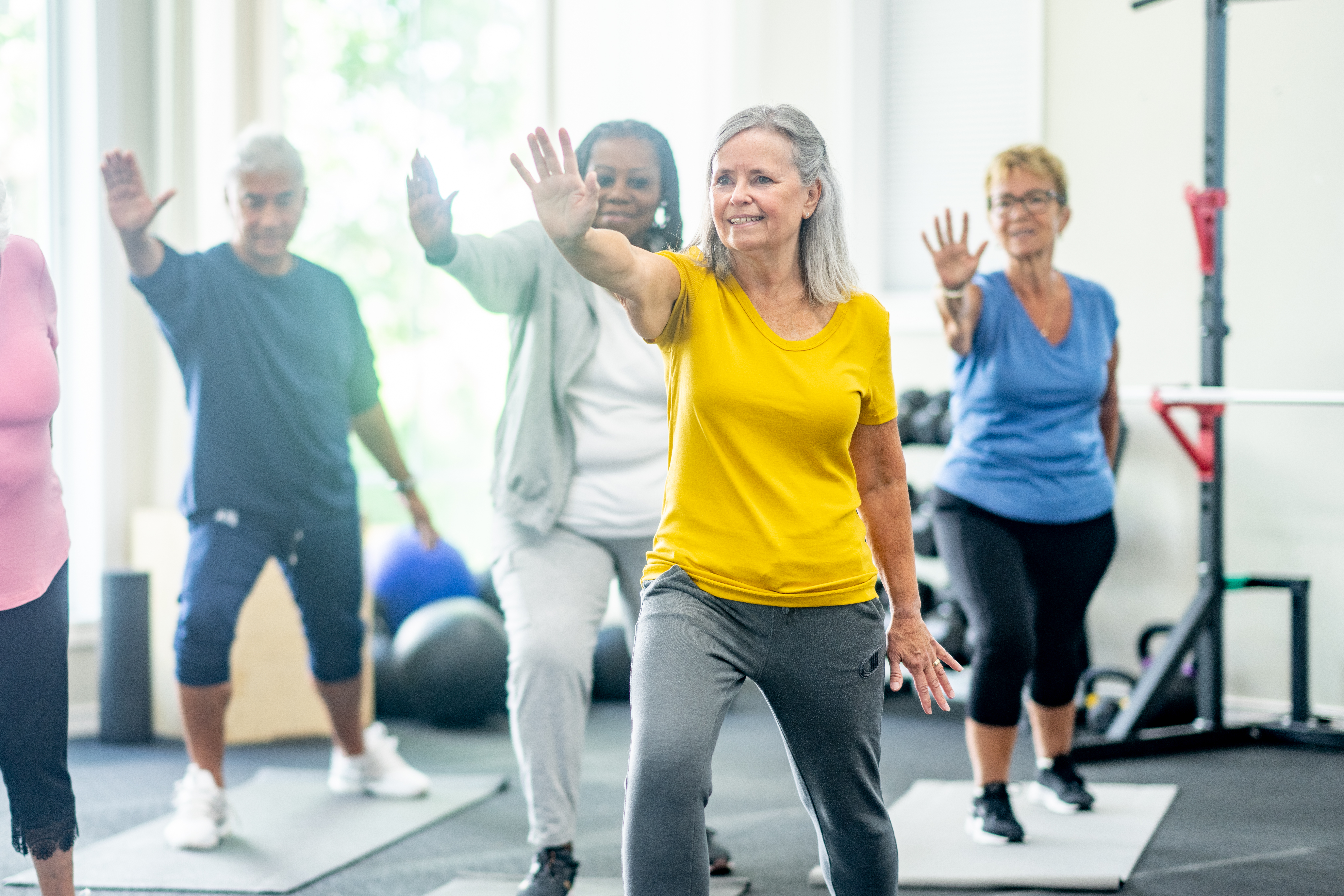 Group exercise participants practising tai chi-style movements in a community fitness class.