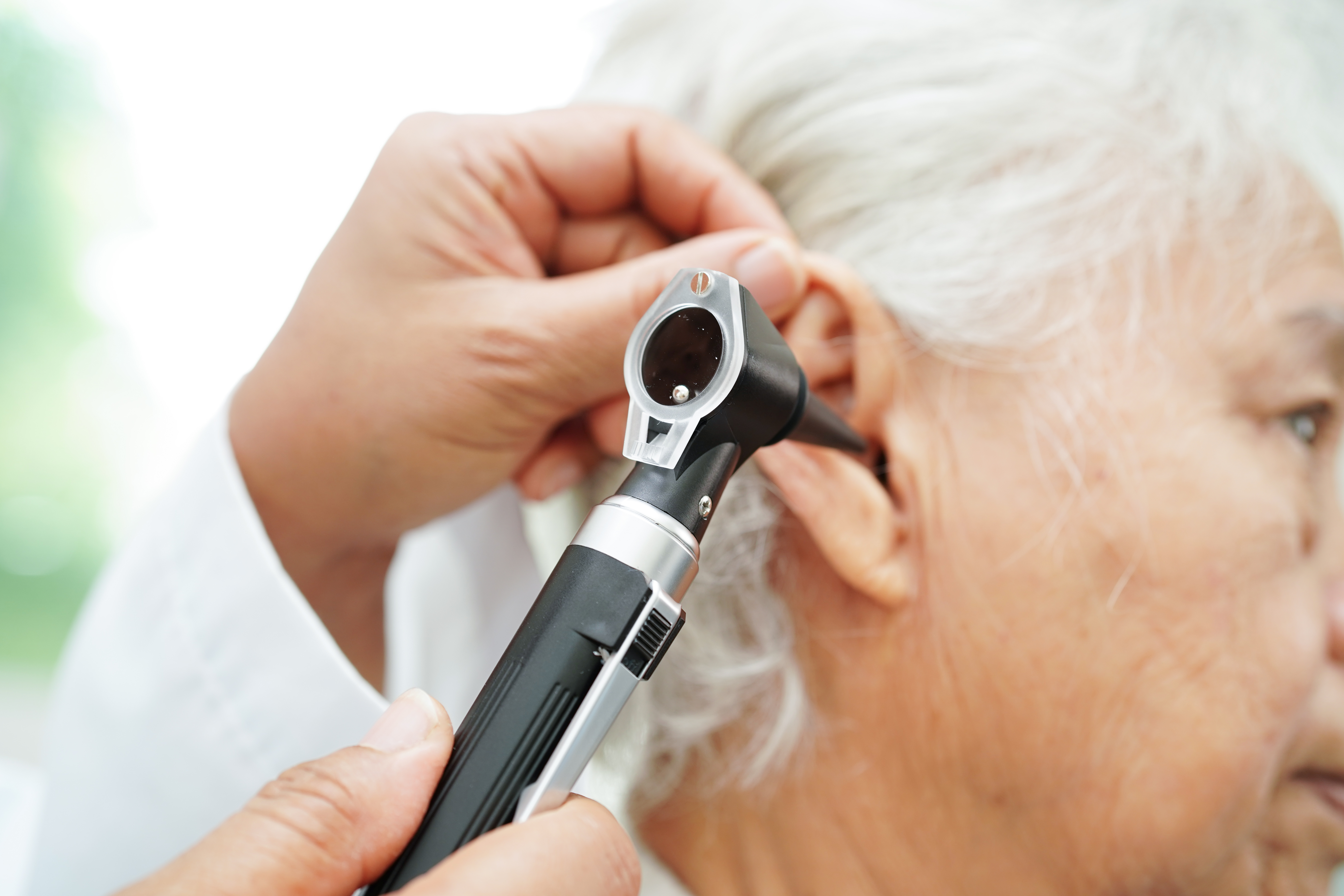 A healthcare professional conducts a hearing check using an otoscope during an ear examination.