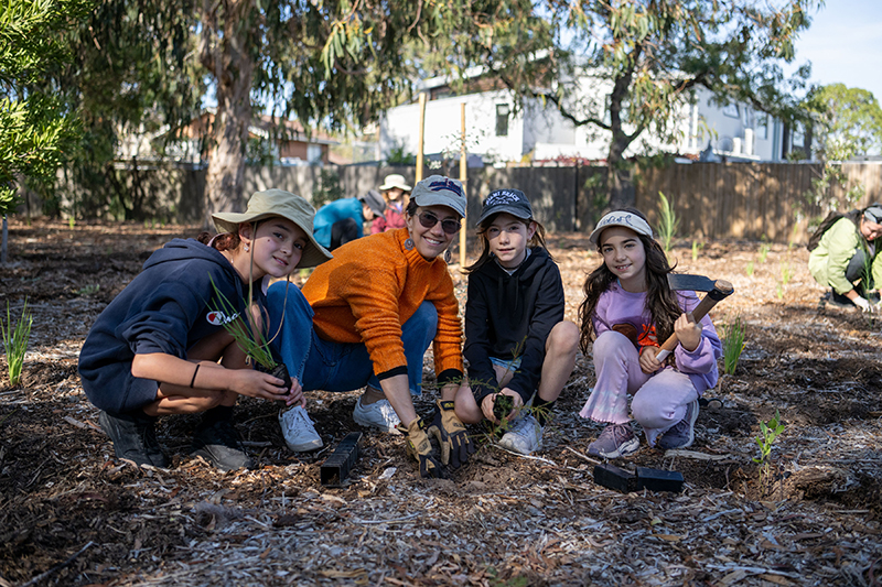 Group of girls and a parent planting plants
