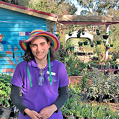 person wearing a purple t-shirt and rainbow coloured hat in plant nursery