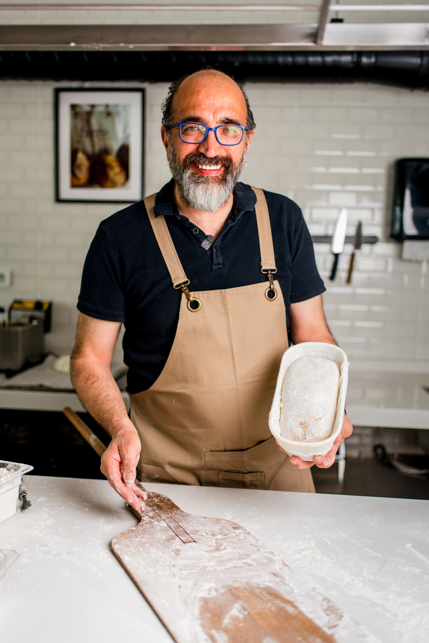 A sourdough baking instructor holds a loaf tin with rising dough during a hands-on sourdough making workshop.