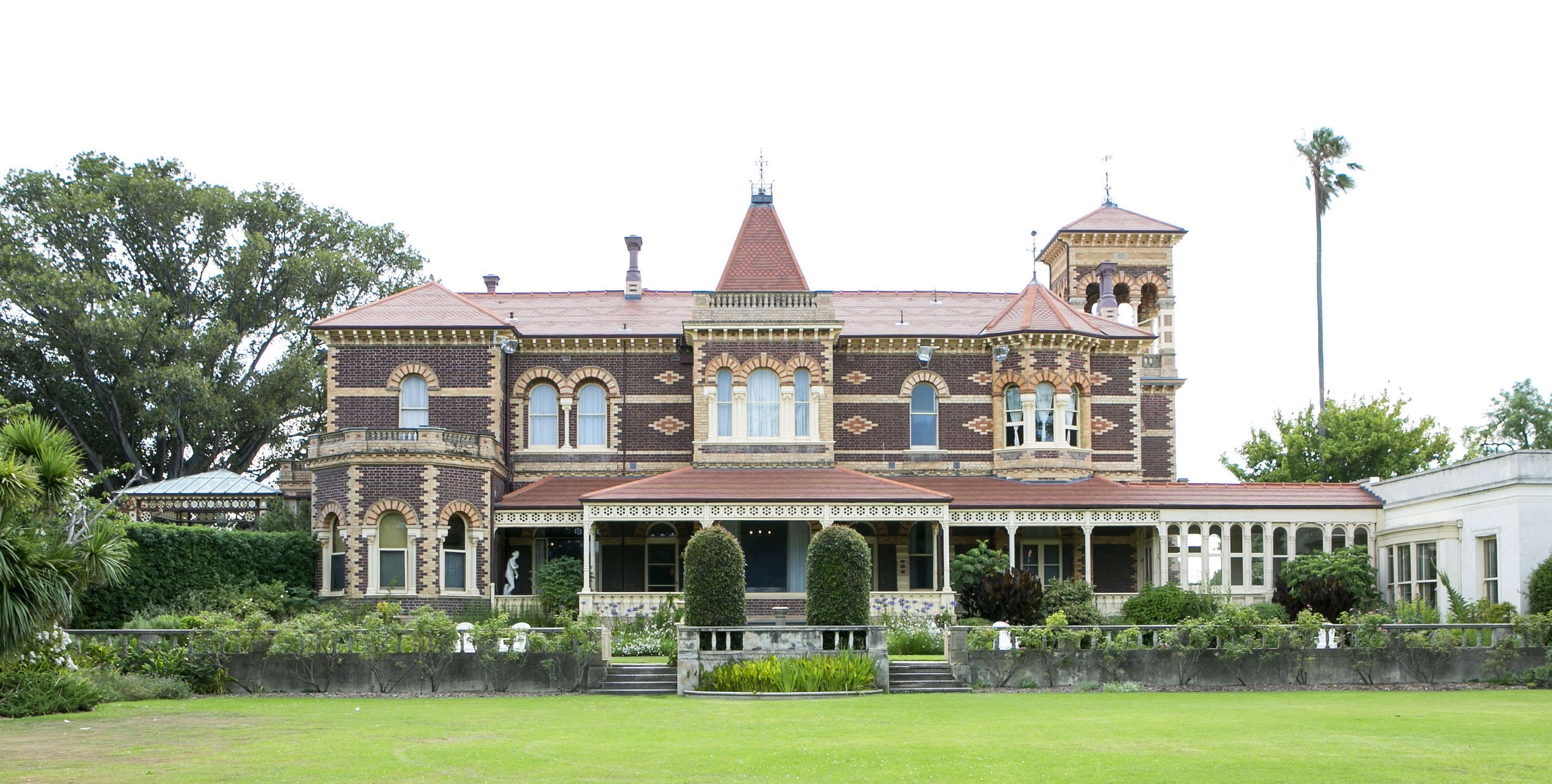 Historic Rippon Lea Estate mansion viewed from the lawn, featuring a two-storey brick façade, verandahs and landscaped gardens.